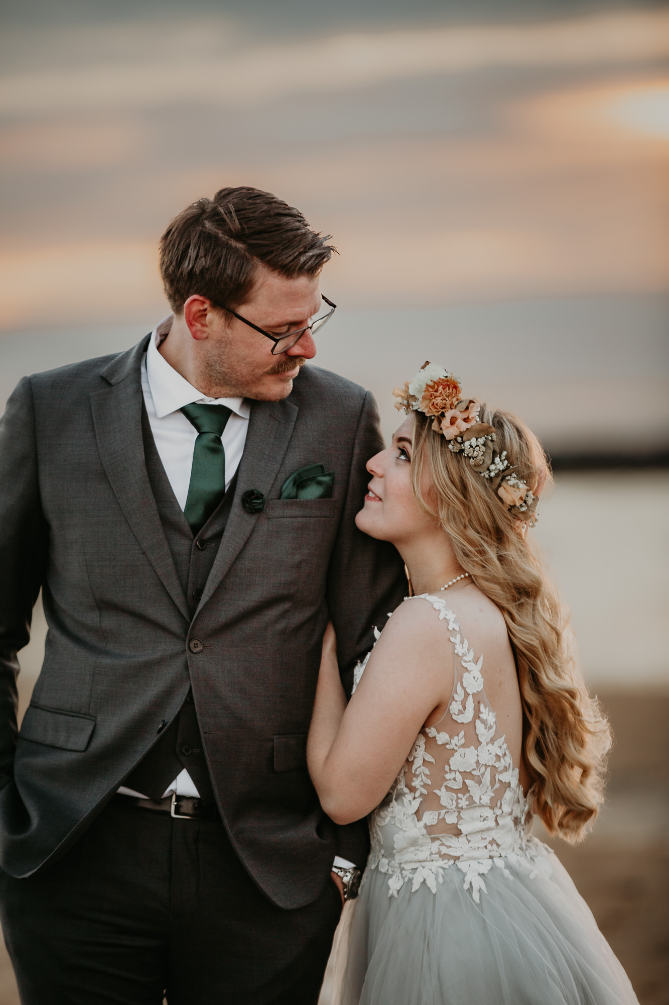 Kärlekfulla nygifta par på stranden under solnedgång.