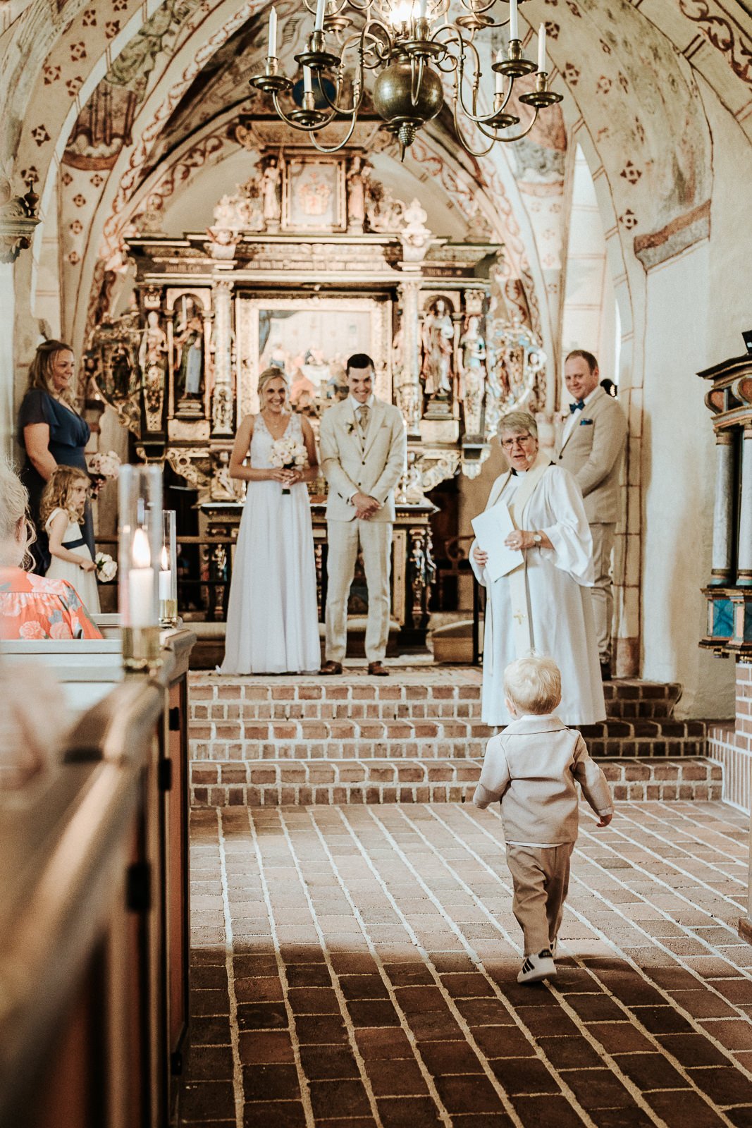 Bröllopsceremoni i Fulltofta kyrka i Skåne med par som går genom kyrkgången i ett klassiskt kyrkorum med högt valv och detaljerad interiör
