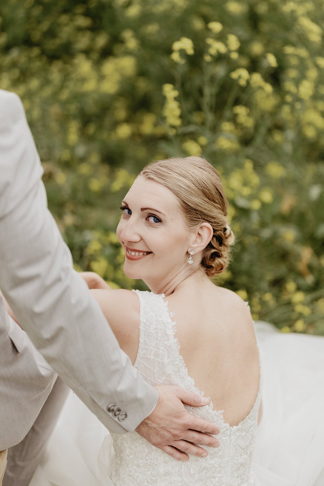 Par står tillsammans i ett blommande rapsfält vid Ringsjön i Skåne under bröllopsfotografering med mjukt kvällsljus