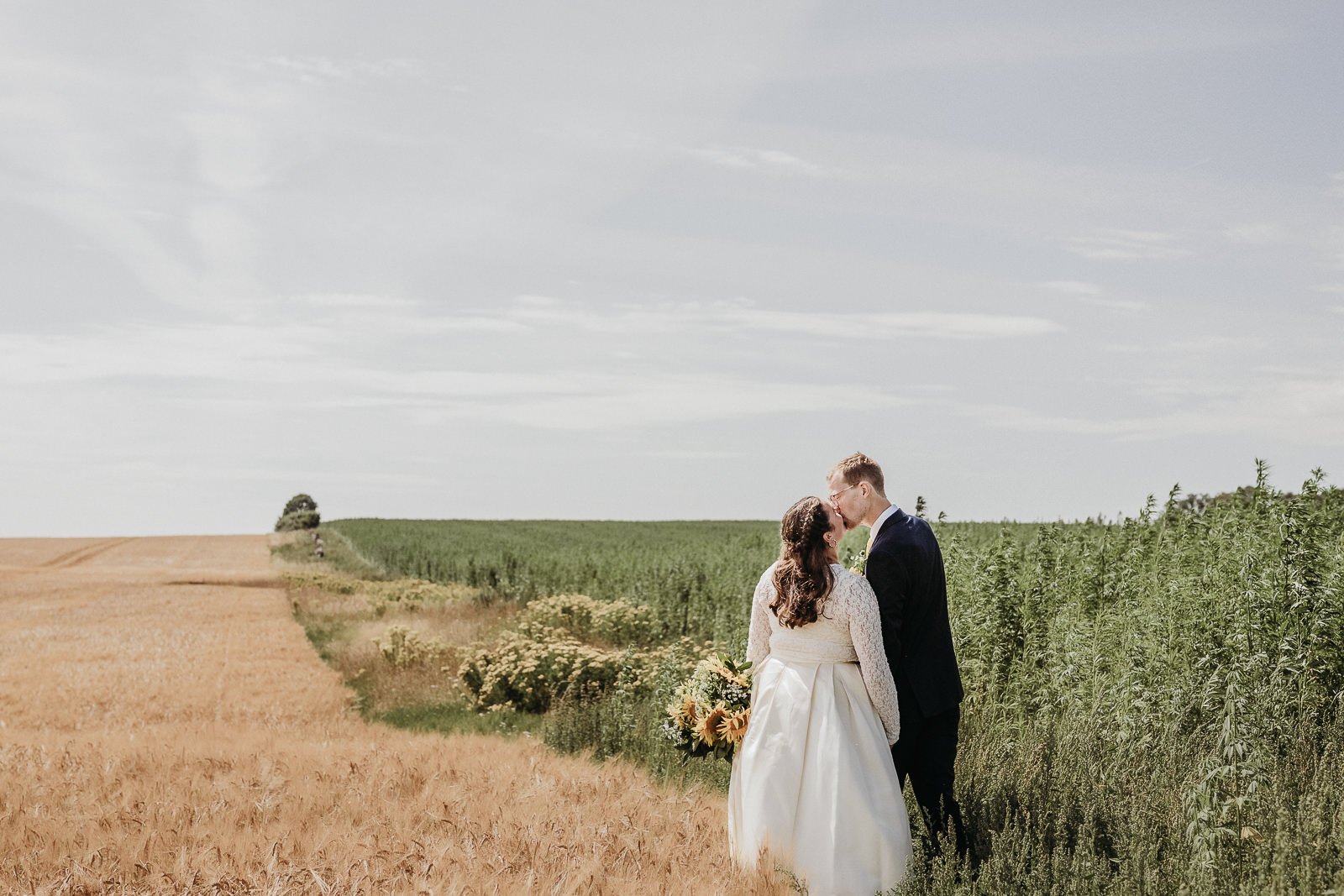Brudpar fotograferat på ett fält i Skåne under bröllopsfotografering av Fotoepok.